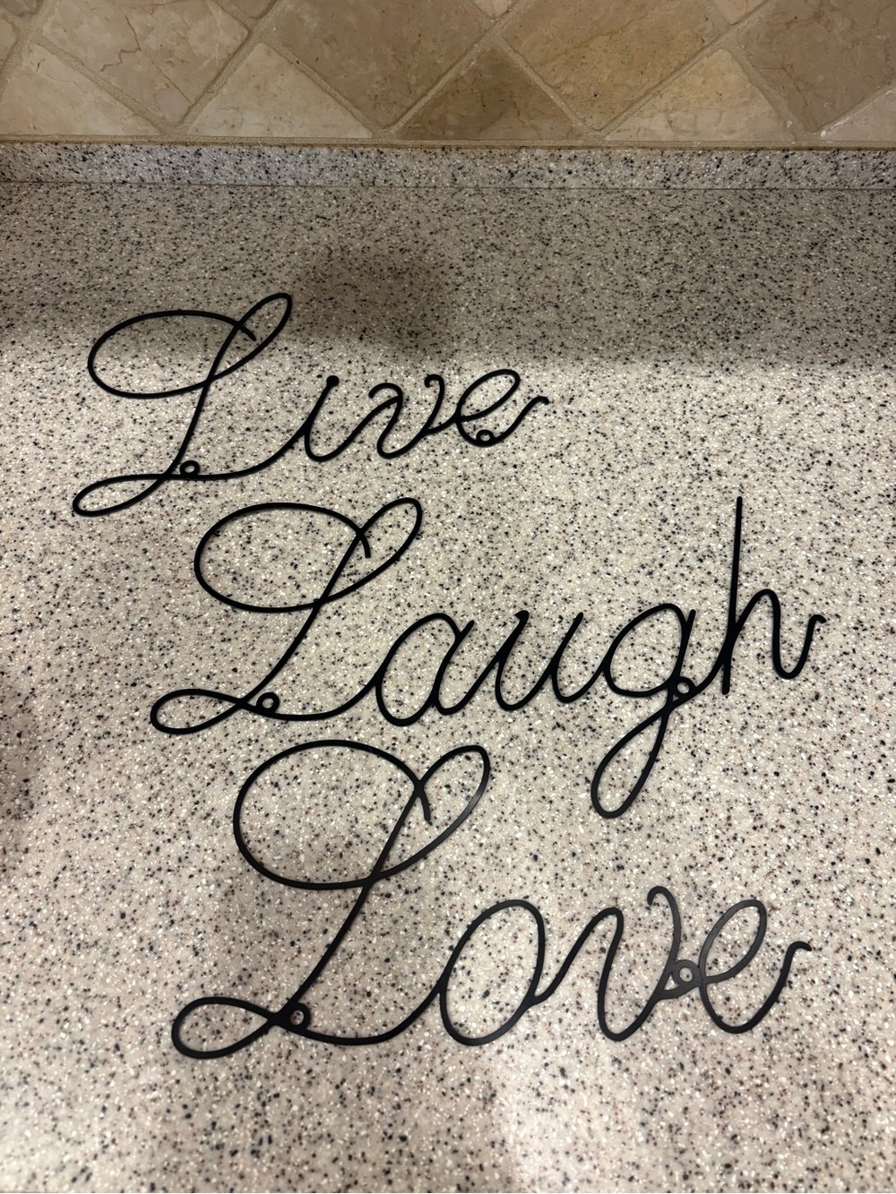 Black metal cursive wall art sign that says "Live Laugh Love".
